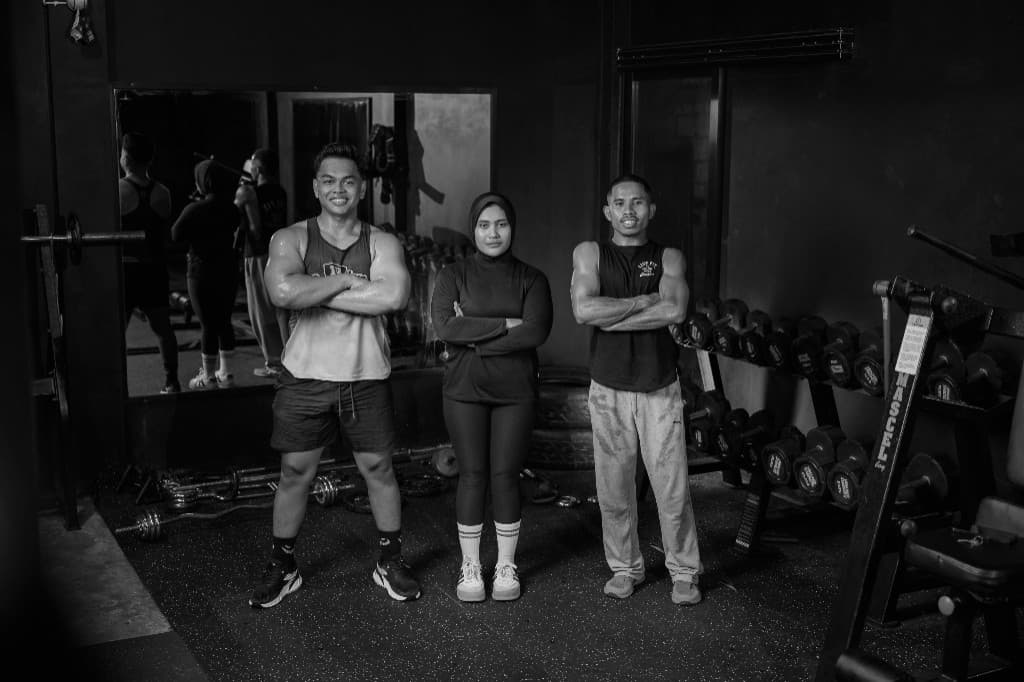 Three coaches standing together in a gym